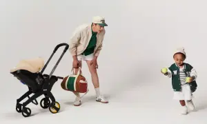 En man med en barnvagn och en sportväska. Barnet leker med tennisbollar. Bältesskydd barnvagn för extra komfort.