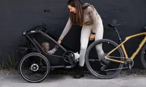 Kvinna med barn i en Thule barnvagn, redo för cykeltur.