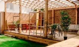 En mysig uteplats med träpergola, bänkar och växter. Perfekt för att måla tryckimpregnerat trä och njuta av sommaren.