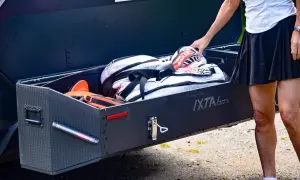 En person lägger ner en sportväska i en robust låda, en perfekt lösning för förvaring bakom din lastbox dragkrok.