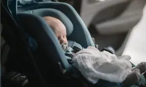 Sovande bebis med napp i en Thule babysitter, tryggt och bekvämt för resan.