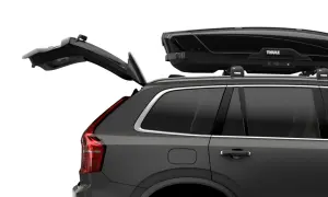 Mörkgrå bil med öppen baklucka och en svart takbox, Thule Motion XT Alpine, på taket. Perfekt för bilsemester.