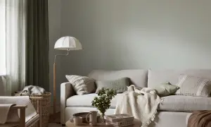 Lugnt och harmoniskt vardagsrum med ljus soffa, gröna kuddar och en vit golvlampa. Perfekt måla vardagsrum inspiration för en avslappnad atmosfär.