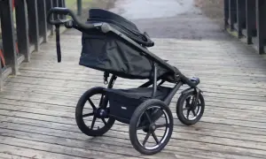 En svart Thule Urban Glide 1 barnvagn står på en träbro. Den är redo för äventyr i stadsmiljö eller på stigar.