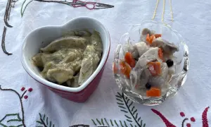 Två skålar med sill och grönsaker, en i hjärtformad skål, förbereds för ett litet julbord.