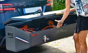 En person packar ner utrustning i en robust låda, en av många praktiska Thule produkter, fäst på en Tesla.