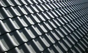 Grå takpannor i ett mönster, med solljus som skapar skuggor. Kanske dags att måla takpannor för att fräscha upp huset?