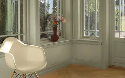 En ljus hall med en vit stol och en vas med blommor på fönsterbrädan. Perfekt måla hall inspiration för en lugn och inbjudande atmosfär.