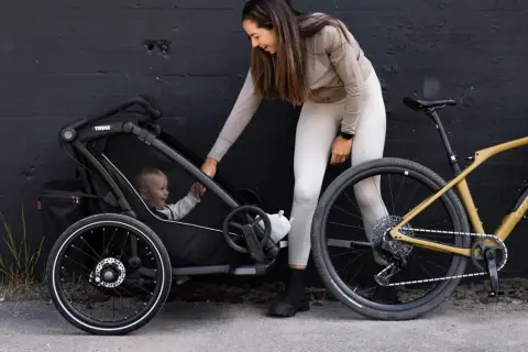 Kvinna med barn i en Thule barnvagn, redo för cykeltur.