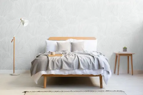 Sovrum med säng, grå pläd, träbricka med mugg och en golvlampa. Vacker tapet med organiskt mönster skapar en lugn boho chic inredning.