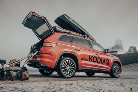 En orange Skoda Kodiaq redo för vinterns äventyr med takboxar och packning.