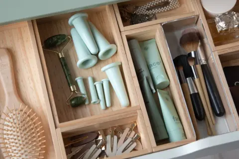 En organiserad låda med skönhetsprodukter, inklusive en jade roller, borstar och krämer. Perfekt för att rensa hemmet och skapa ordning.