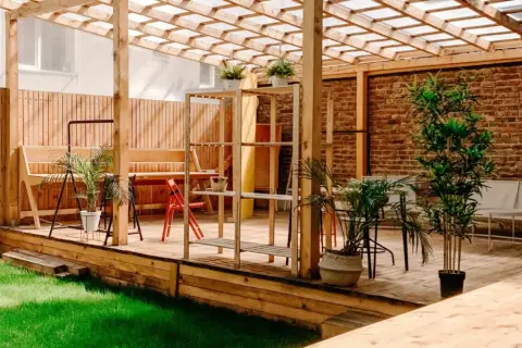 En mysig uteplats med träpergola, bänkar och växter. Perfekt för att måla tryckimpregnerat trä och njuta av sommaren.