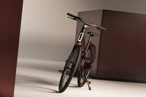 Mörkröd elcykel med integrerad belysning och genomgående axel, redo för stadens äventyr.