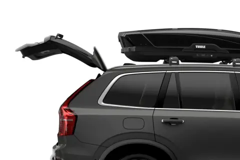 Mörkgrå bil med öppen baklucka och en svart takbox, Thule Motion XT Alpine, på taket. Perfekt för bilsemester.