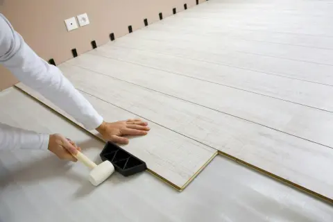 Lägger ett nytt golv av oljad ek. En hammare används för att fästa ihop plankorna.