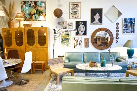 En ljus och luftig butik med 60 tals inredning. En ljusgrön soffa, teakskåp, konst och speglar skapar en retrokänsla.
