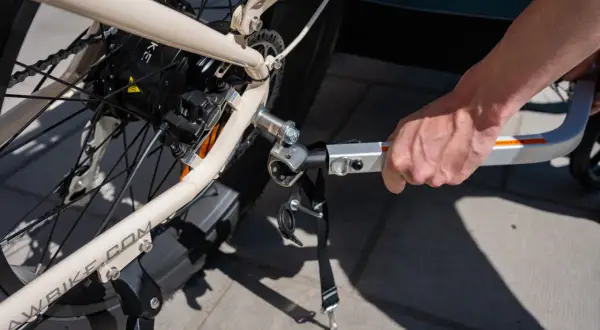 Hand fäster en Thule Ezhitch-koppling på en elcykel för att dra en cykelkärra.