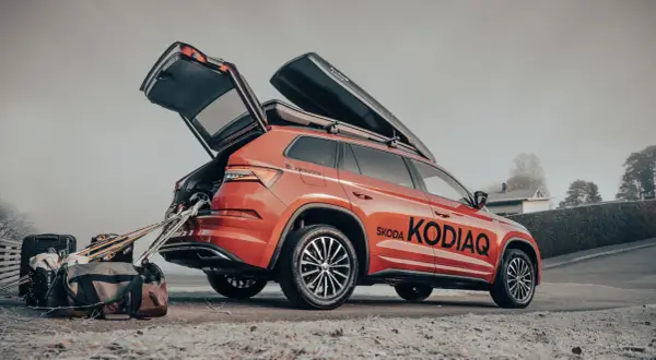 En orange Skoda Kodiaq redo för vinterns äventyr med takboxar och packning.