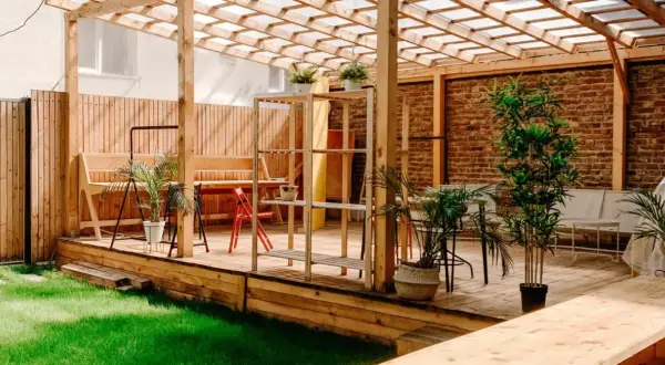 En mysig uteplats med träpergola, bänkar och växter. Perfekt för att måla tryckimpregnerat trä och njuta av sommaren.