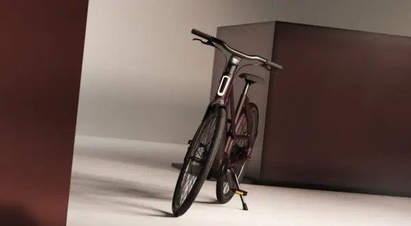 Mörkröd elcykel med integrerad belysning och genomgående axel, redo för stadens äventyr.