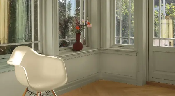 En ljus hall med en vit stol och en vas med blommor på fönsterbrädan. Perfekt måla hall inspiration för en lugn och inbjudande atmosfär.