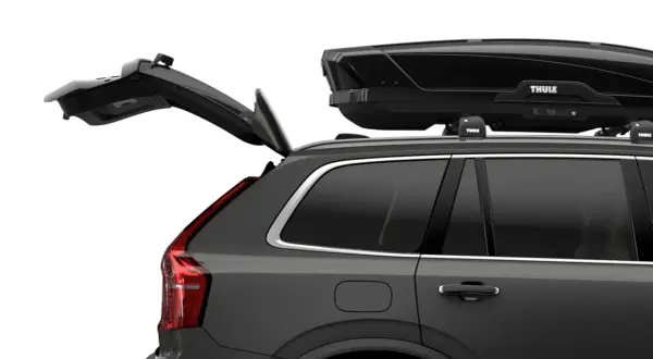 Mörkgrå bil med öppen baklucka och en svart takbox, Thule Motion XT Alpine, på taket. Perfekt för bilsemester.