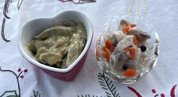 Två skålar med sill och grönsaker, en i hjärtformad skål, förbereds för ett litet julbord.