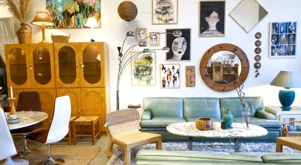 En ljus och luftig butik med 60 tals inredning. En ljusgrön soffa, teakskåp, konst och speglar skapar en retrokänsla.