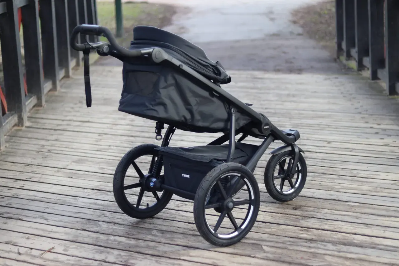 En svart Thule Urban Glide 1 barnvagn står på en träbro. Den är redo för äventyr i stadsmiljö eller på stigar.