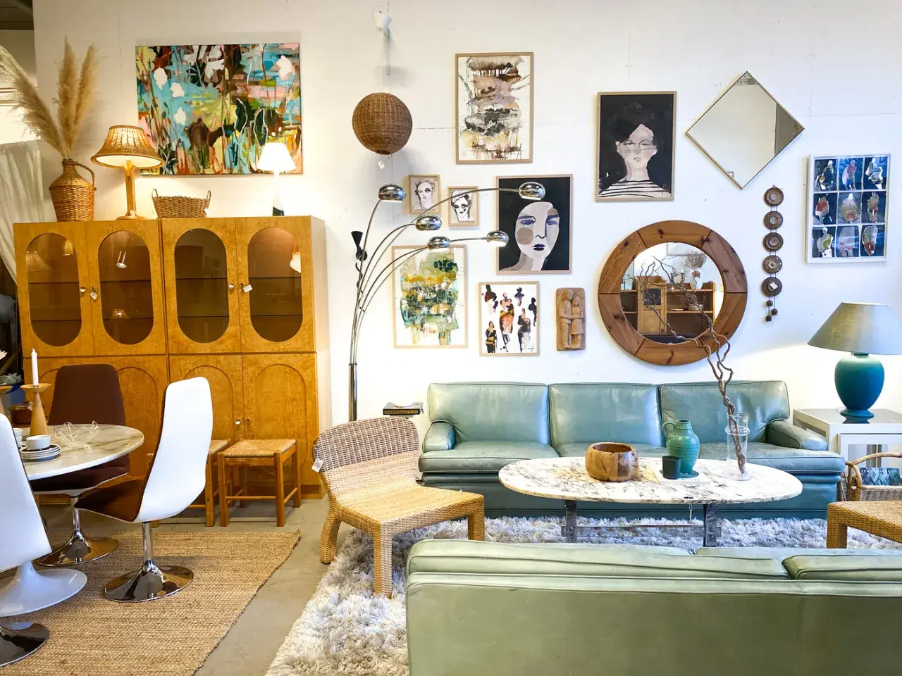 En ljus och luftig butik med 60 tals inredning. En ljusgrön soffa, teakskåp, konst och speglar skapar en retrokänsla.