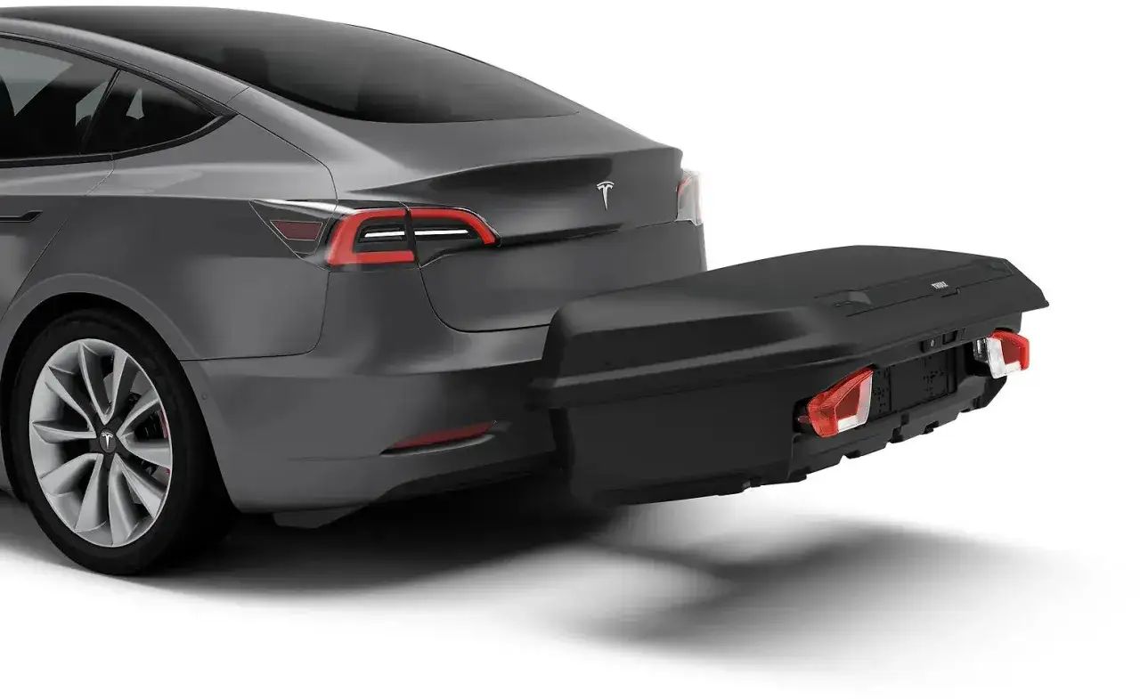 Gr&aring; Tesla med en svart lastbox monterad p&aring; dragkrok. Perfekt f&ouml;r extra f&ouml;rvaring p&aring; resan.