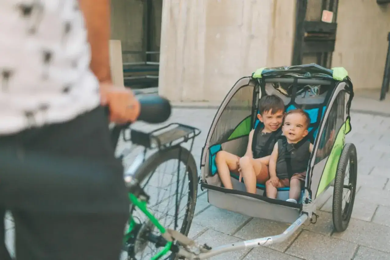 Tv&aring; glada barn sitter i en cykelvagn bebis, redo f&ouml;r en tur.