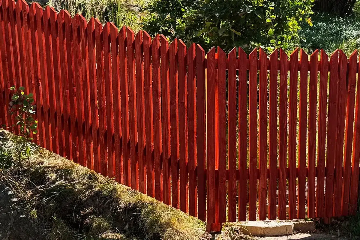 Nyligen färdigställt, ett vackert rött staket som ramar in trädgården. Perfekt för att bygga staket och skapa en mysig utomhusmiljö.