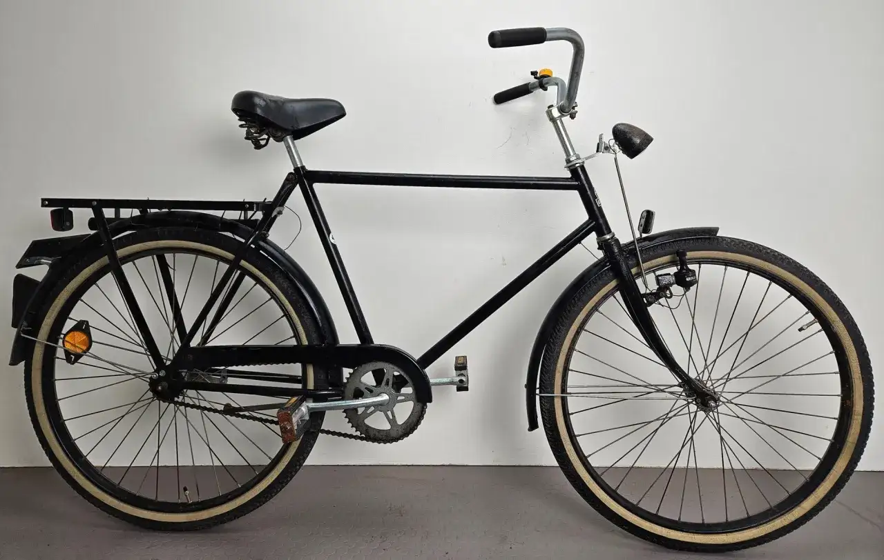 Svart cykel med paketh&aring;llare och klassiska d&auml;cksidor. Perfekt f&ouml;r dig som s&ouml;ker kronan cykel reservdelar f&ouml;r att h&aring;lla din trotj&auml;nare i toppskick.