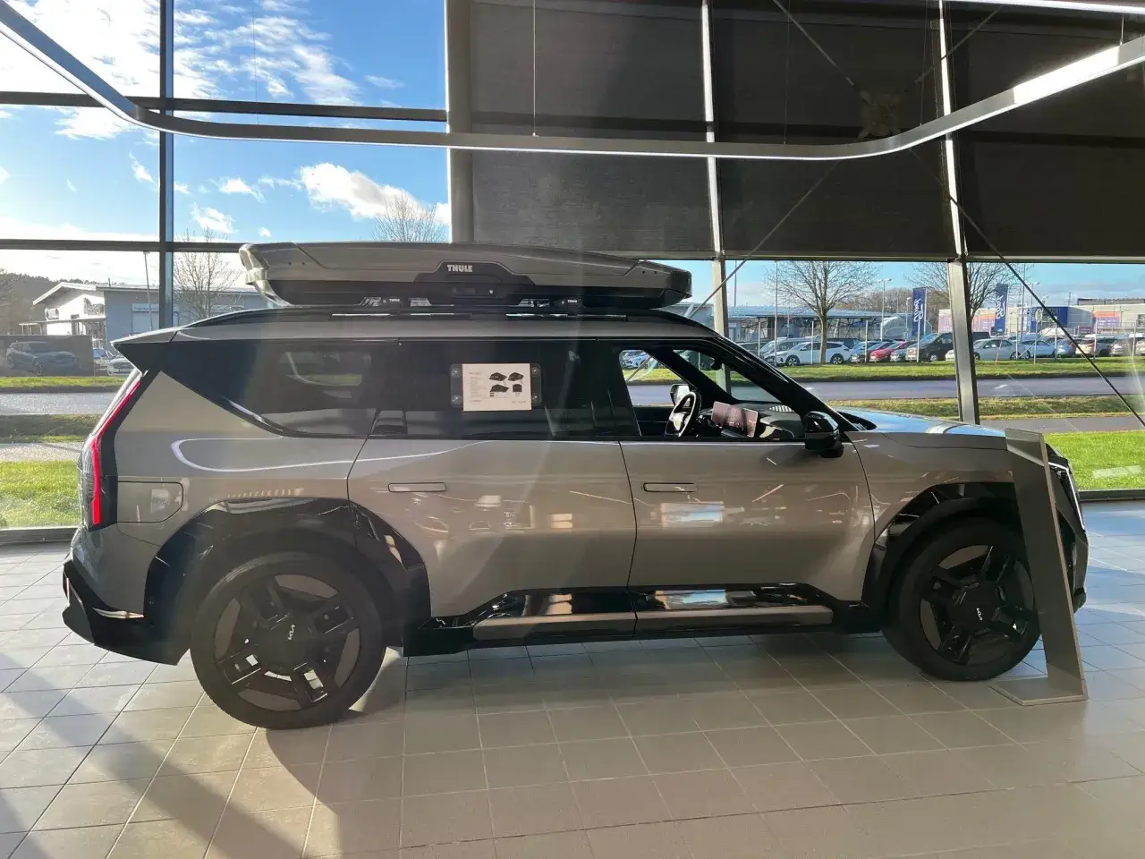 Gr&aring; elbil med takboxen Thule Motion XT Alpine redo f&ouml;r &auml;ventyr.