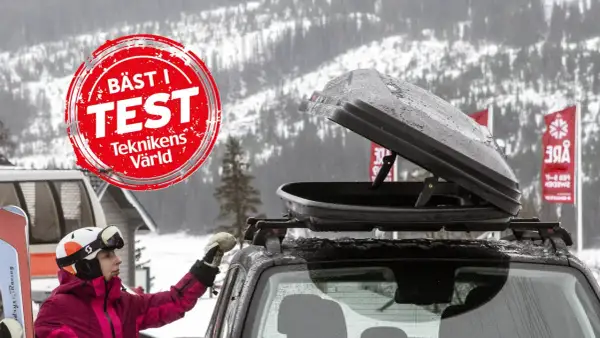 En person med skidor och hjälm förbereder en takbox för en skidresa. "Bäst i test"-märkning syns.