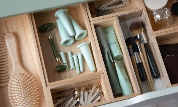 En organiserad låda med skönhetsprodukter, inklusive en jade roller, borstar och krämer. Perfekt för att rensa hemmet och skapa ordning.