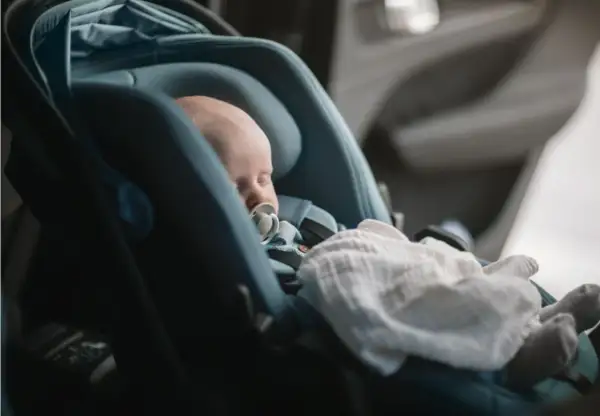 Sovande bebis med napp i en Thule babysitter, tryggt och bekvämt för resan.