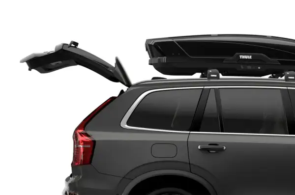 Mörkgrå bil med öppen baklucka och en svart takbox, Thule Motion XT Alpine, på taket. Perfekt för bilsemester.
