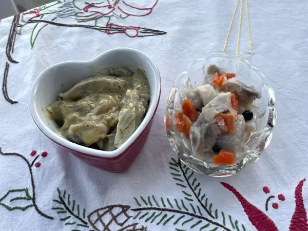 Två skålar med sill och grönsaker, en i hjärtformad skål, förbereds för ett litet julbord.